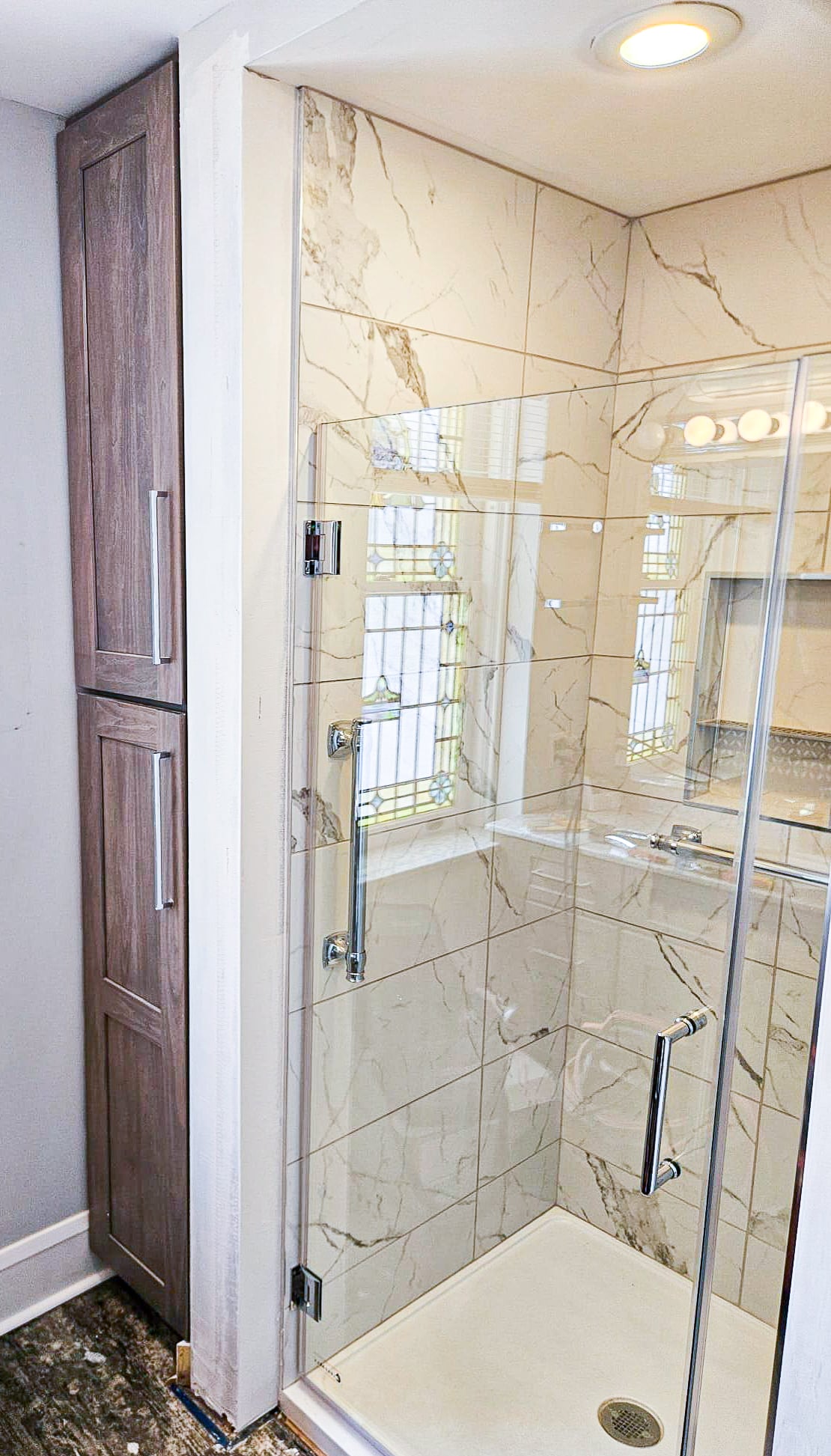 Custom marble walk-in shower with frameless glass and built-in niche — after Wahl remodel